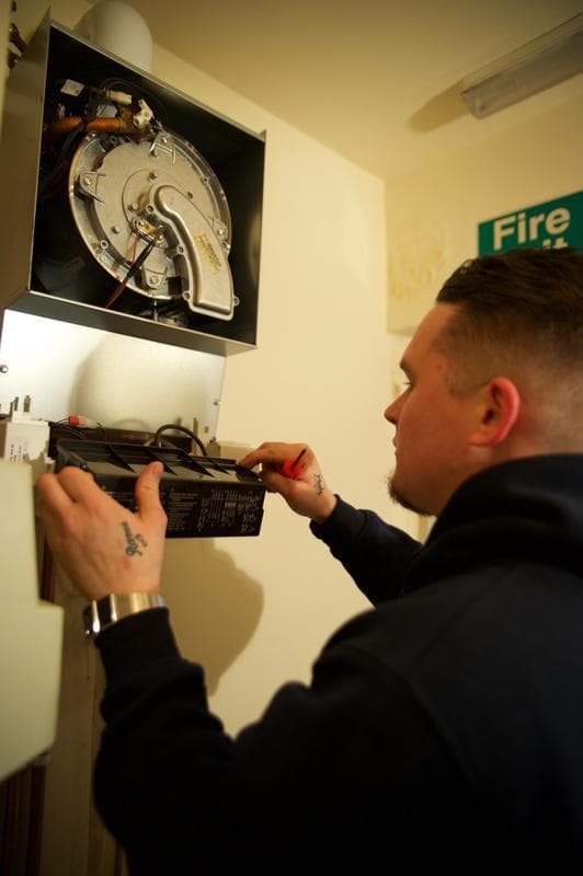 Home Comfort Assured Renewables engineer working on heating controls and appliance internals during a visit